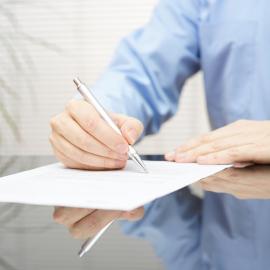 Man signs form with pen.